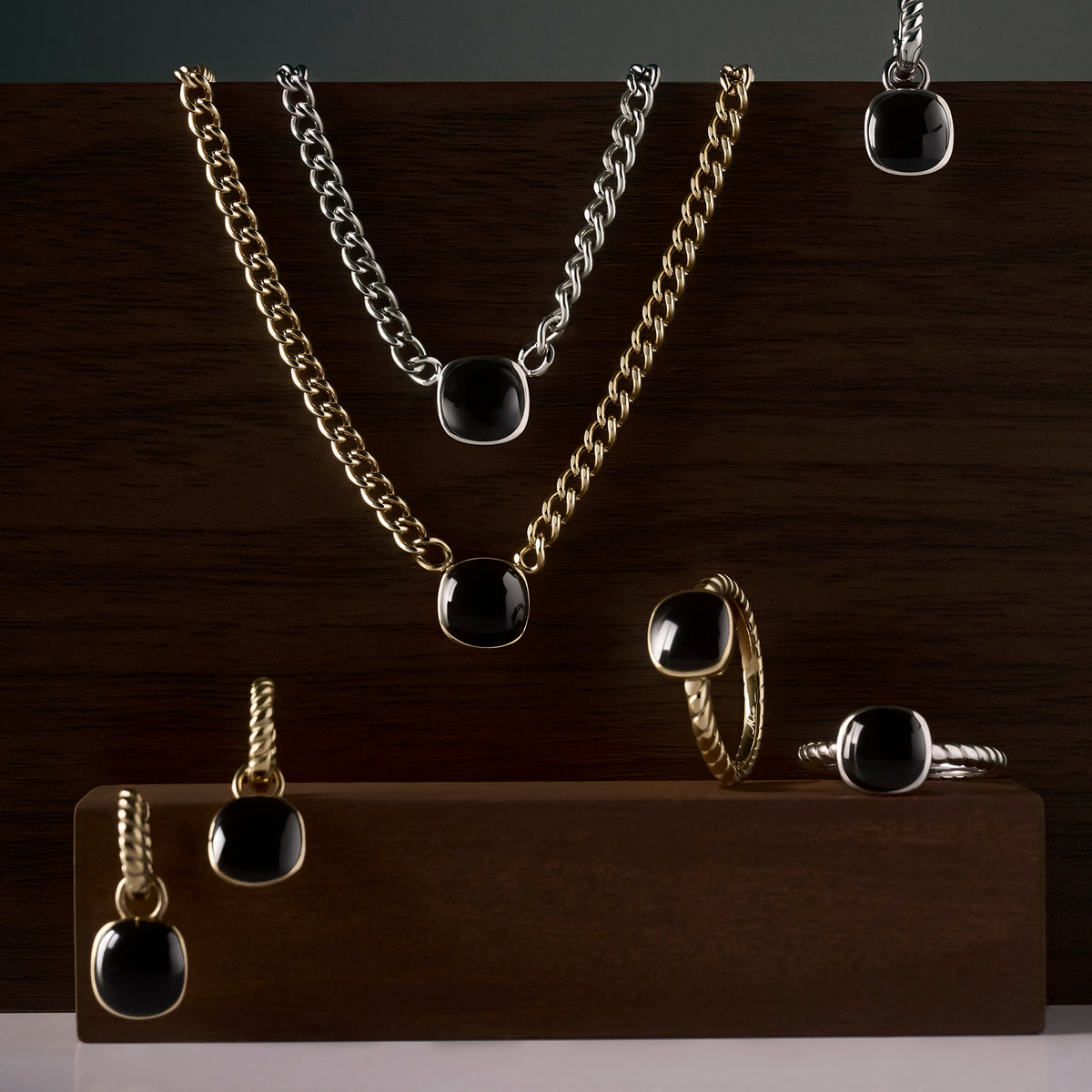 Black gemstone jewelry collection with gold and silver stainless steel pendant necklaces, drop earrings and twisted band rings, bold modern statement pieces with polished black stones.